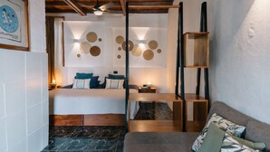 Ein modernes Hotelzimmer mit einem Bett, einer Holzbalkendecke, einem Marmorboden, einer Couch und einer Wand mit runden Verzierungen.