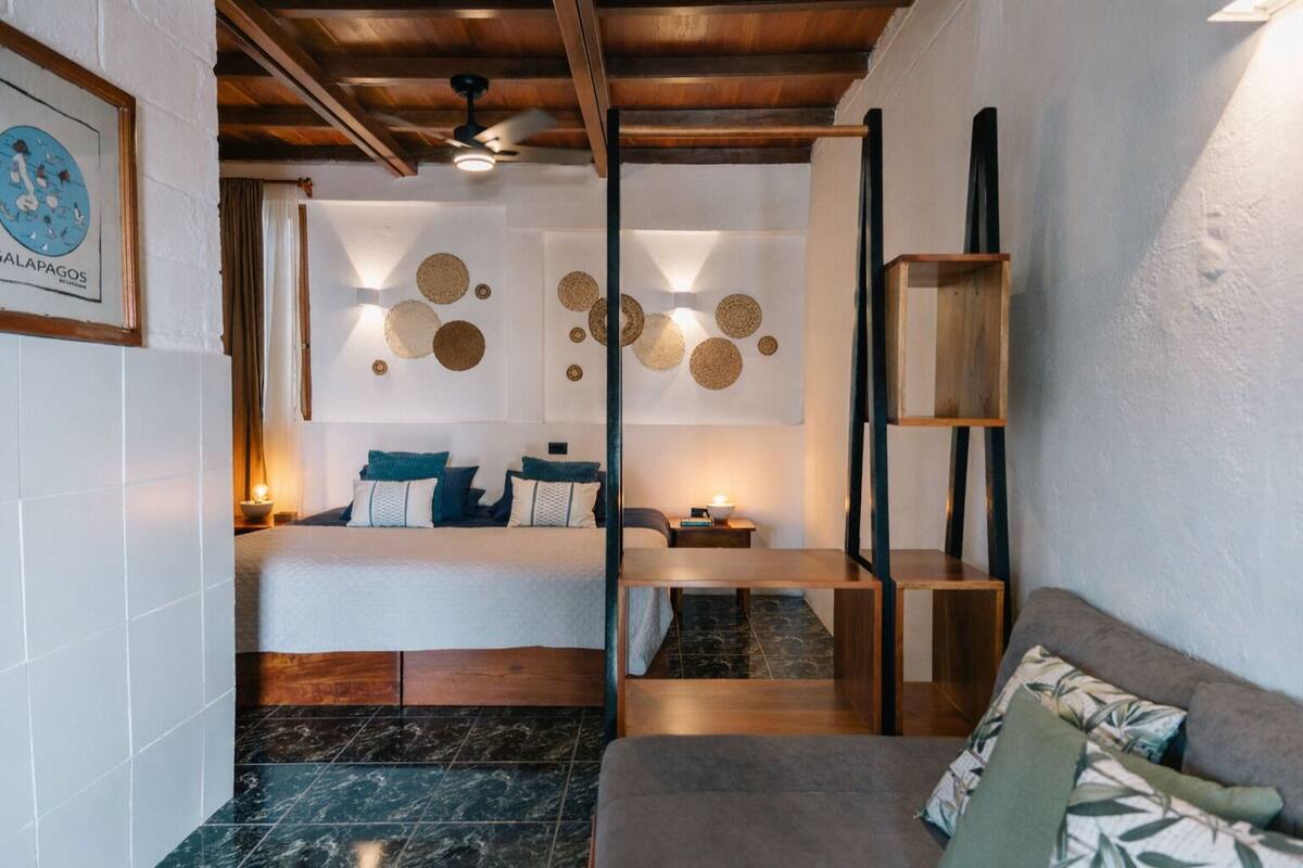 A modern hotel room with a bed, a wooden ceiling, a marble floor, a sofa, and a wall with circular decorations.