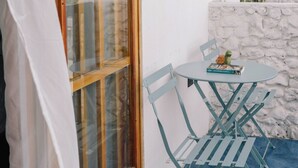 Ein kleiner Sitzbereich im Freien mit Tisch, Stühlen, einem Buch und einem Blumentopf.