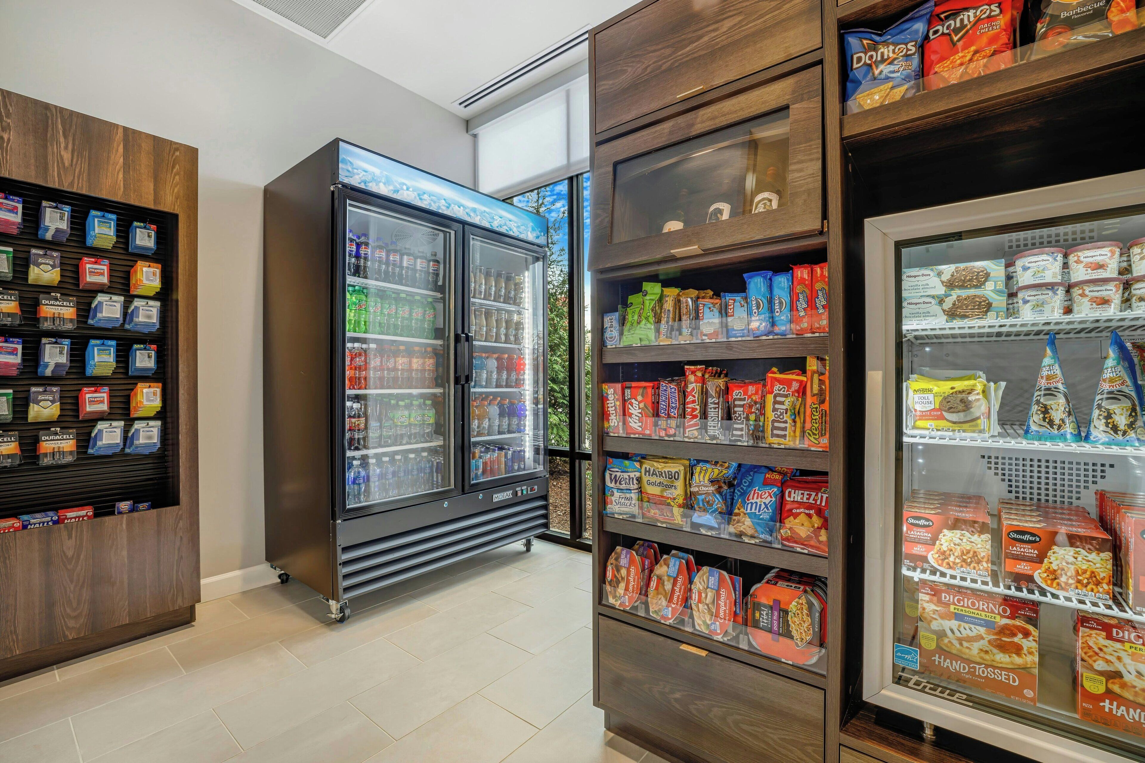 Una máquina expendedora con aperitivos y un expositor refrigerado con alimentos congelados.
