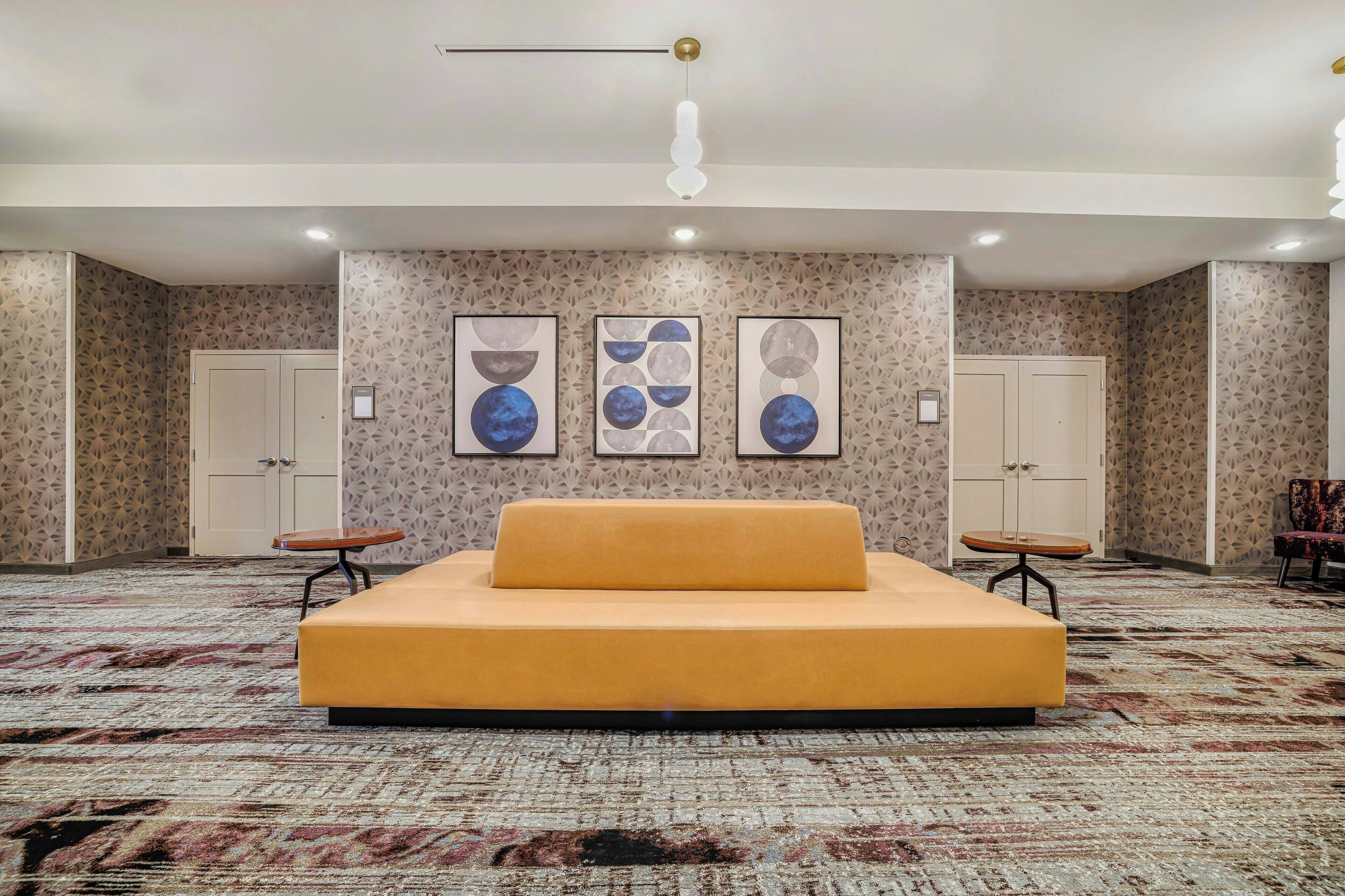 Een hotelkamer met een groot bed, twee kasten, een tafeltje en een stoel. Er hangen drie kunstwerken in de lijst aan de muur.
