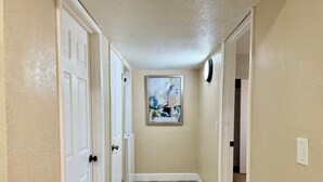 A hallway with white doors, a wooden floor, and a painting on the wall.