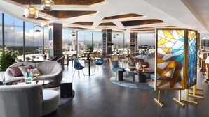A spacious lounge with modern furniture, large windows offering city views, and a unique stained glass partition. - Novotel Nairobi Westlands (Nairobi)