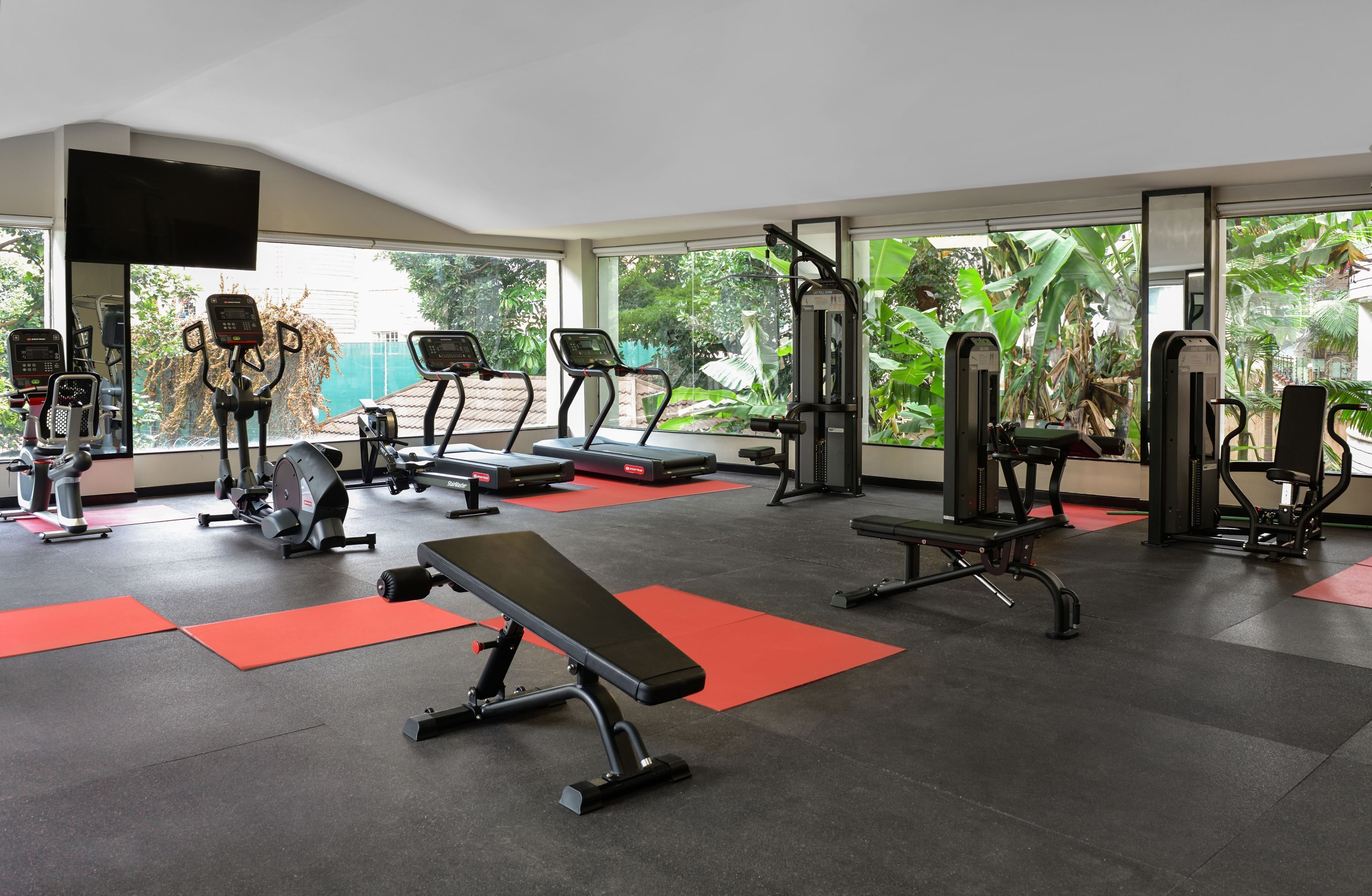 A gym with treadmills, weight machines, and a bench.