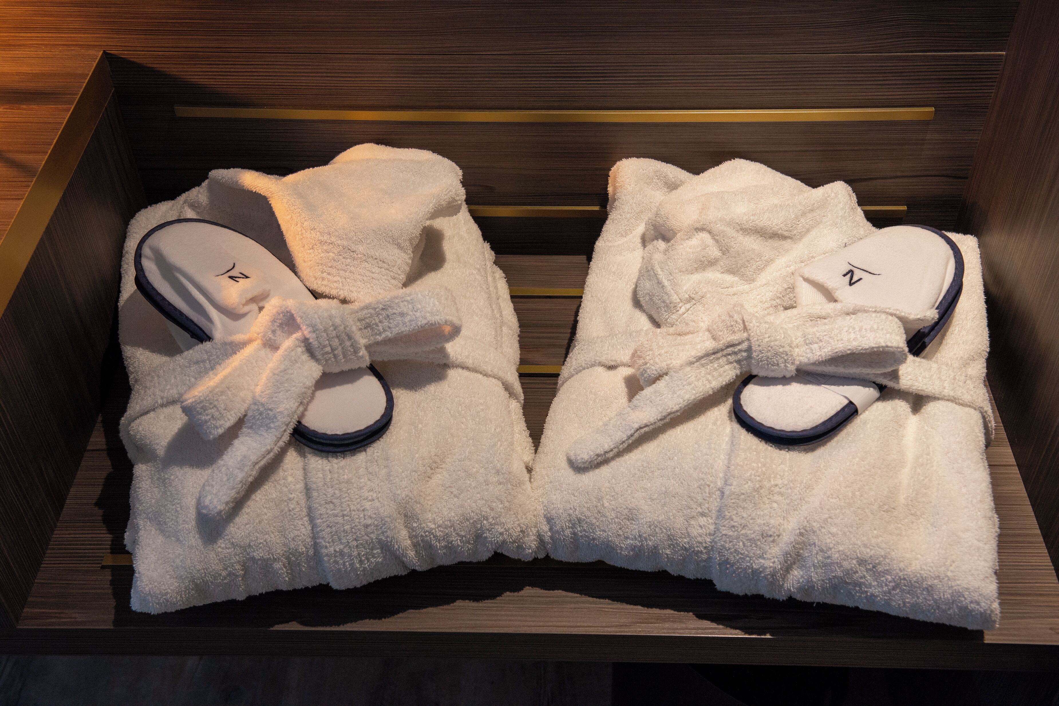 A wooden drawer with two white bathrobes tied with a bow.