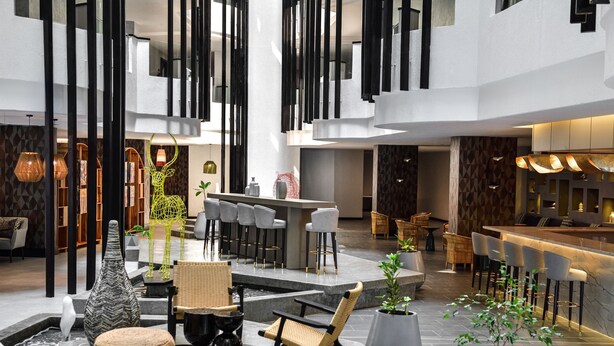 A modern lobby with a bar area, seating arrangements, and decorative elements like vases and plants. - Novotel Nairobi Westlands (Nairobi)