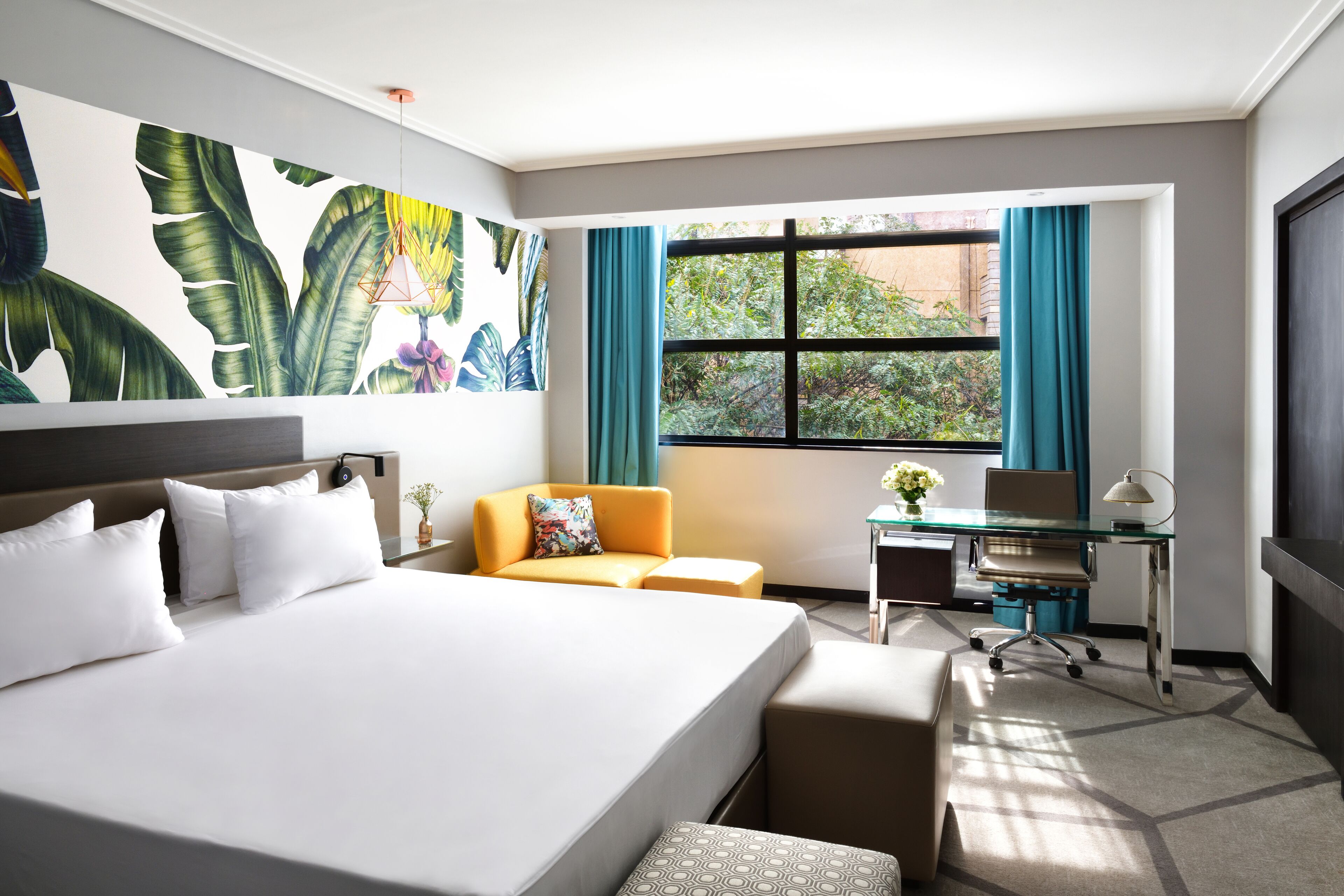 A hotel room with a large bed, a desk, a chair, and a window with curtains.