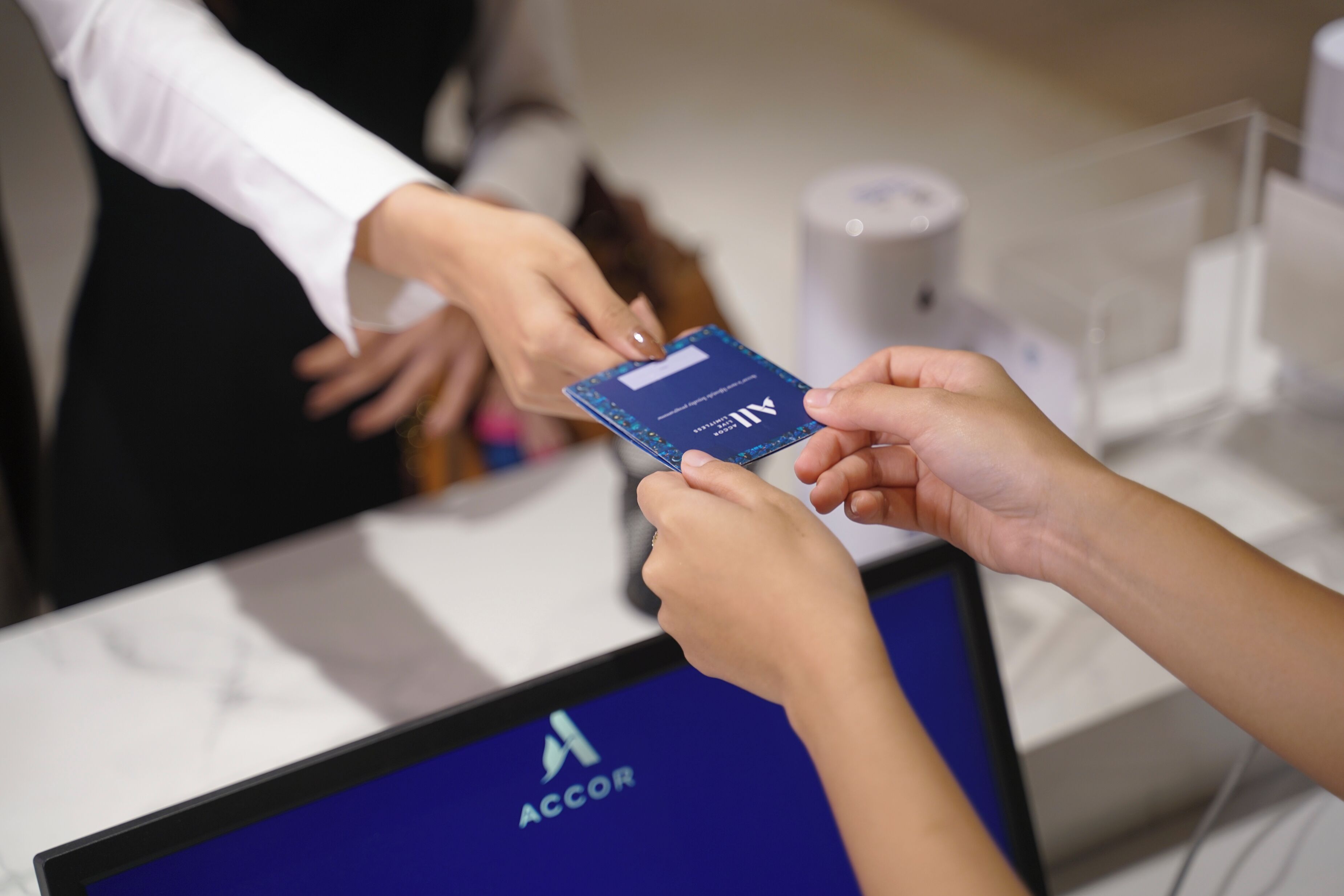 A person holding a card with the ACCOR logo, indicating a membership or loyalty card.
