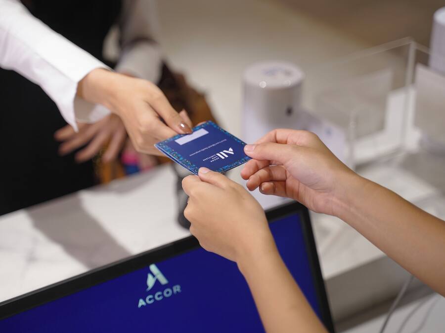 Eine Person hält eine Karte mit dem ACCOR-Logo, vermutlich eine Mitglieds- oder Treuekarte.