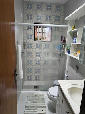 A bathroom with a shower, toilet, and sink. - Portal Flores Suítes (Campos do Jordão)