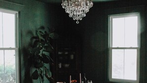 A dining room with a chandelier, a large window, and a plant.