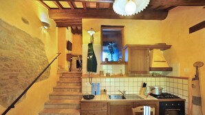 Eine kompakte Küche mit einer Holztreppe, einem Essbereich mit Tisch für zwei Personen und einem kleinen Fenster mit Blick.