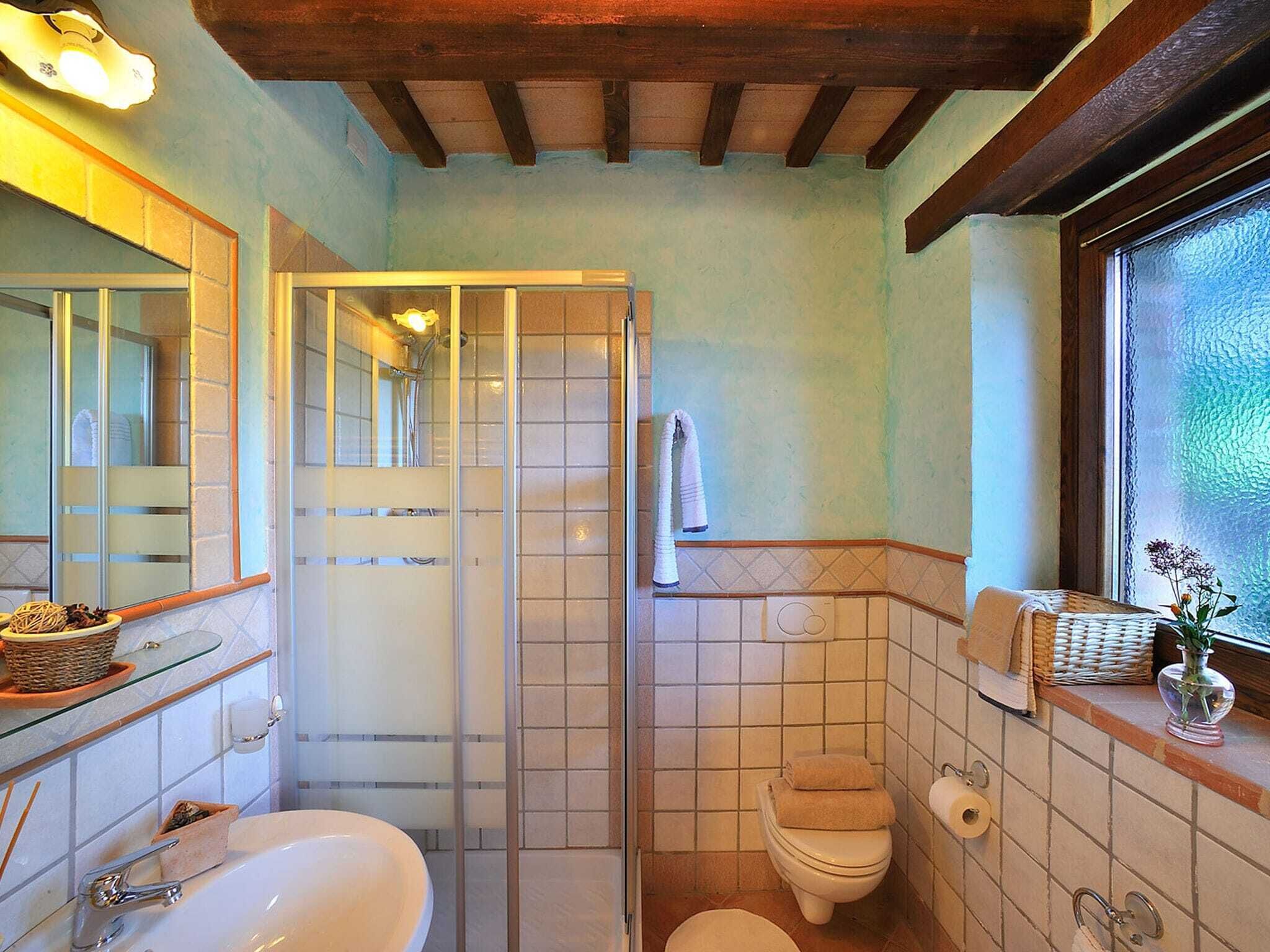 A bathroom with a glass shower enclosure, a toilet, and a sink.