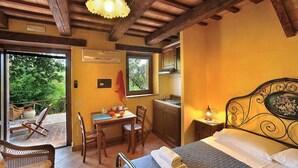 Ein gemütliches Schlafzimmer mit Bett, Esstisch, Stühlen, einer kleinen Küchenzeile und einem Balkon mit Sitzgelegenheit.