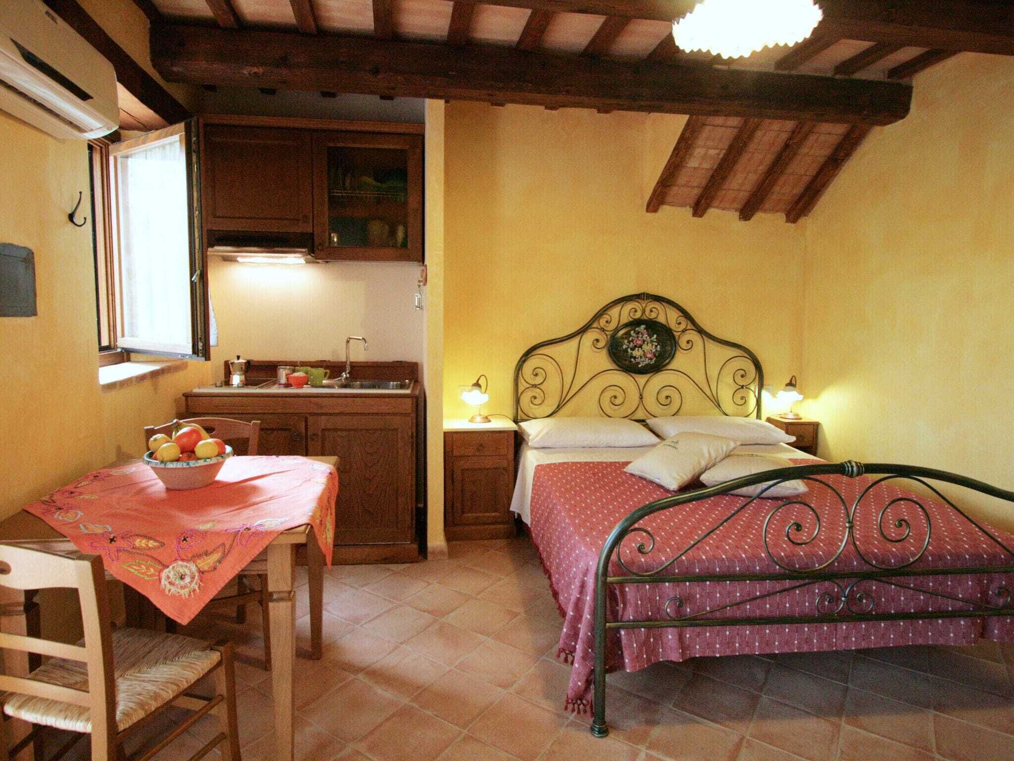 A bedroom with a metal bed frame, a bedside table with a lamp, and a window with curtains.