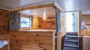A wooden cabin interior with a bunk bed, a small window, and a staircase leading to a loft area. - Idyllic Lakeside Cottage (Florennes)
