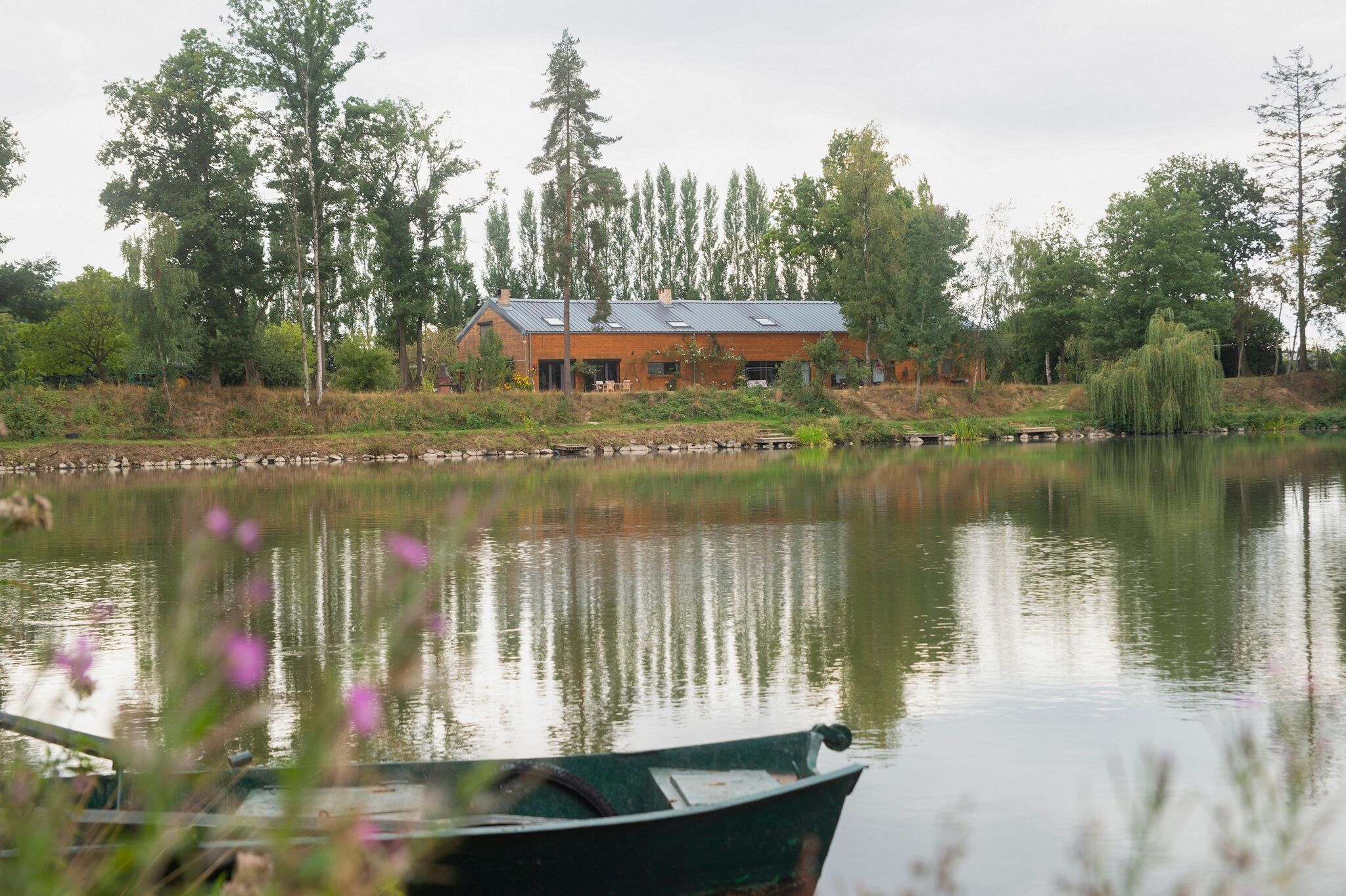 A lakeside house with a dock, surrounded by trees and a calm water body.