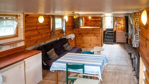 A compact cabin with a wooden interior, a small kitchenette, a sofa, a table, and a bed. - Idyllic Lakeside Cottage (Florennes)