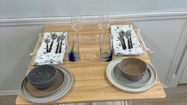 Mesa para dos personas servida con platos, tazones, cubiertos y vasos.