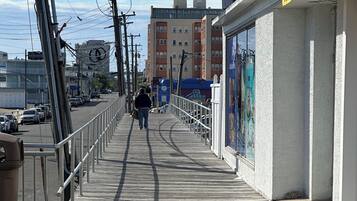Un muelle de madera con un sendero peatonal, postes de servicios públicos y edificios al fondo.