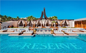 Relax by the pool surrounded by lush greenery and a unique architectural feature.