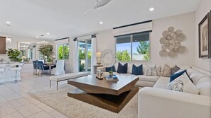 A modern living room with a white sofa, a coffee table, and a dining area with a bar. - Blue Heaven (Roseville)