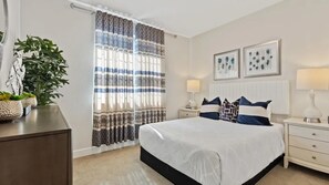 A hotel room with a bed, bedside tables, a lamp, a plant, and a window with curtains. - Blue Heaven (Roseville)