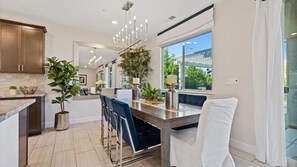 Una cocina moderna con comedor, ventanas amplias y una araña.