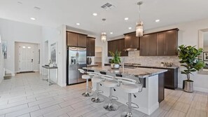 A modern kitchen with a central island, bar stools, stainless steel appliances, and pendant lighting. - Blue Heaven (Roseville)