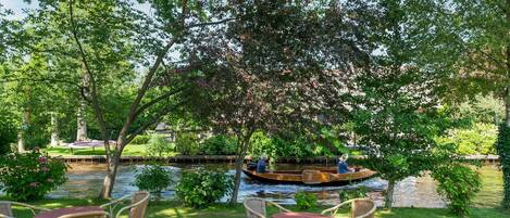 Um jardim à beira-rio com móveis de vime e um barco.