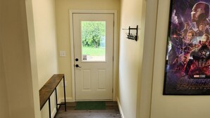 A hallway with a wooden bench, a door with a window, and a poster on the wall. - Family-friendly, playroom w/ air hockey & arcade games, hot tub, mountain views! (Seymour)