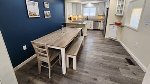 A modern kitchen with white cabinets, a wooden dining table, and a bench. - Family-friendly, playroom w/ air hockey & arcade games, hot tub, mountain views! (Seymour)