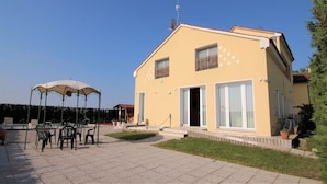 Un bâtiment à deux étages, doté d’un toit plat, de grandes fenêtres et d’un espace extérieur abrité avec des chaises, aménagé pour accueillir des clients.