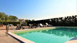 Une piscine avec des chaises longues et un espace de détente abrité.