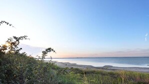 Un paysage côtier avec une plage, de la végétation et un ciel dégagé.