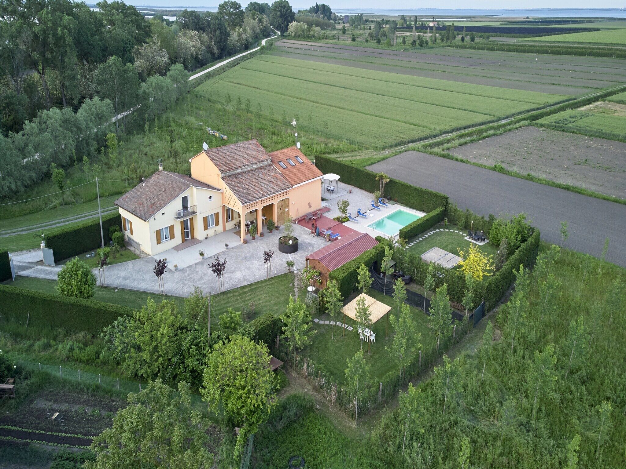 Ett stort hus med en swimmingpool, omgivet av gröna fält och träd.