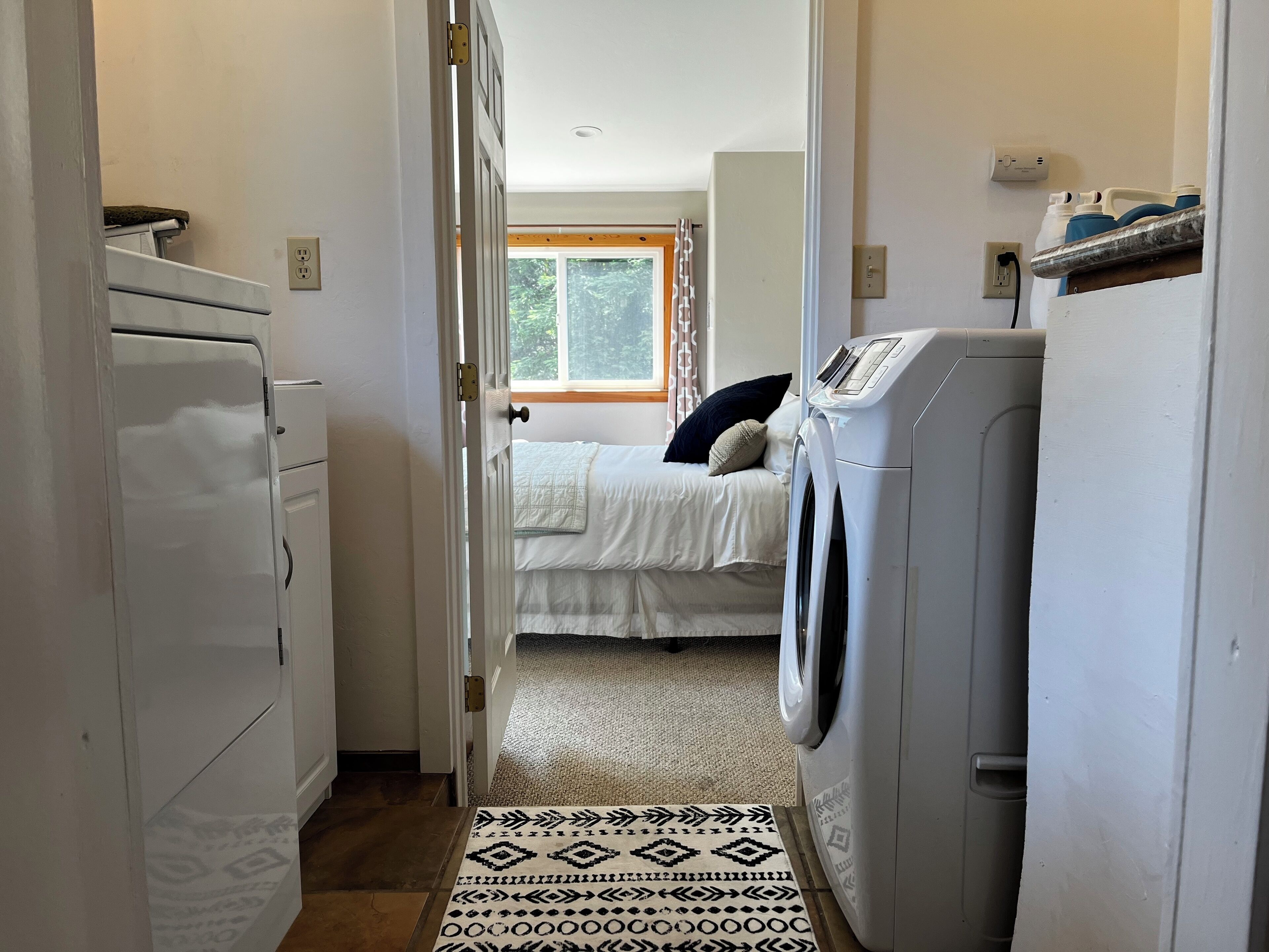 Un corridoio stretto che porta a una camera da letto con un letto, una lavatrice e un'asciugatrice.