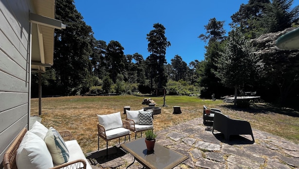 An outdoor patio with wicker furniture, a stone table, and a potted plant.