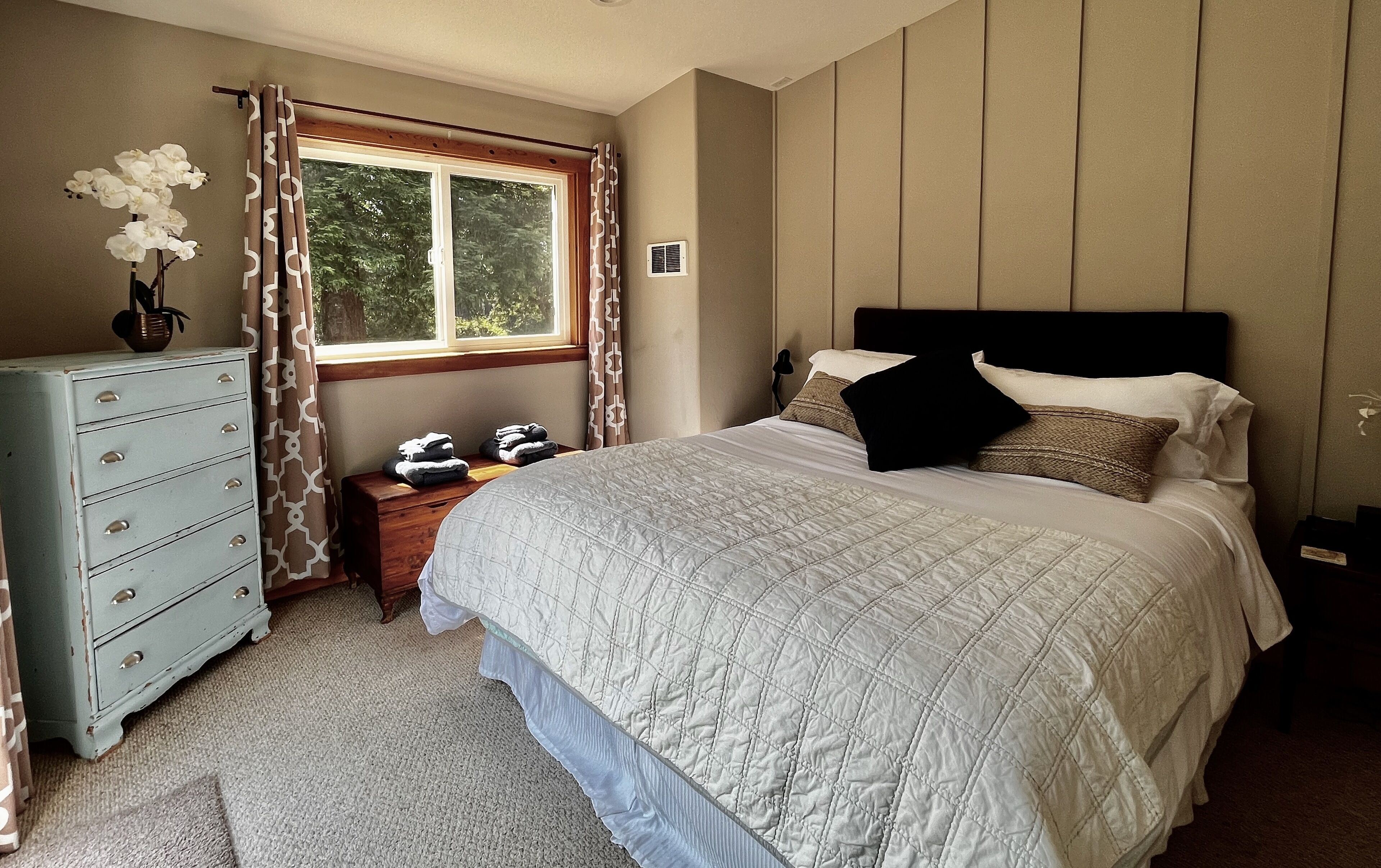 A bedroom with a bed, dresser, and window.