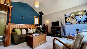 A living room with a blue accent wall, a wooden coffee table, a sofa, a chair, and a TV.