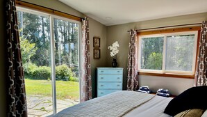A bedroom with a large bed, a dresser, and a window with curtains.