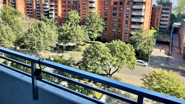 Een wooncomplex met meerdere appartementen gebouwen, omgeven door bomen en een parkeerplaats.