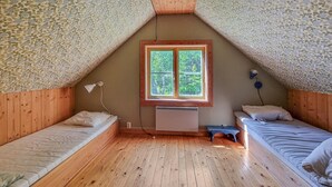 A small attic bedroom with wooden floors, two single beds, a window with a view of greenery, and a radiator. - 3 bedroom cozy home in Mellerud (Mellerud)