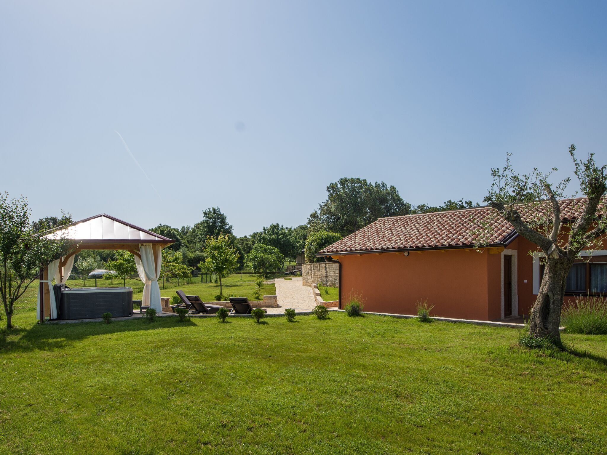 A house with a tiled roof, a covered outdoor seating area, and a lawn.
