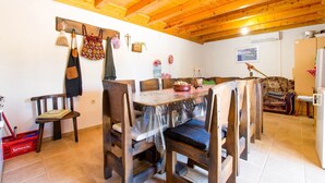 A wooden dining area with a table and chairs, a wooden ceiling, and a red basket on the floor. - Holiday Home in Seline near the Sea (Seline)
