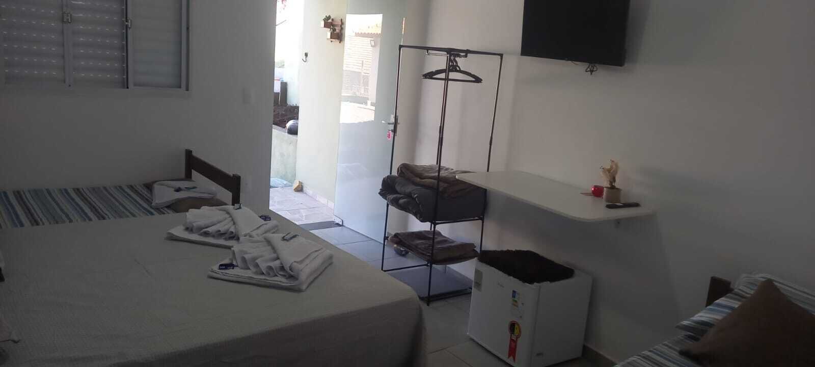 A hotel room with a bed, a desk, a chair, a TV, a wardrobe, and a small trash bin.