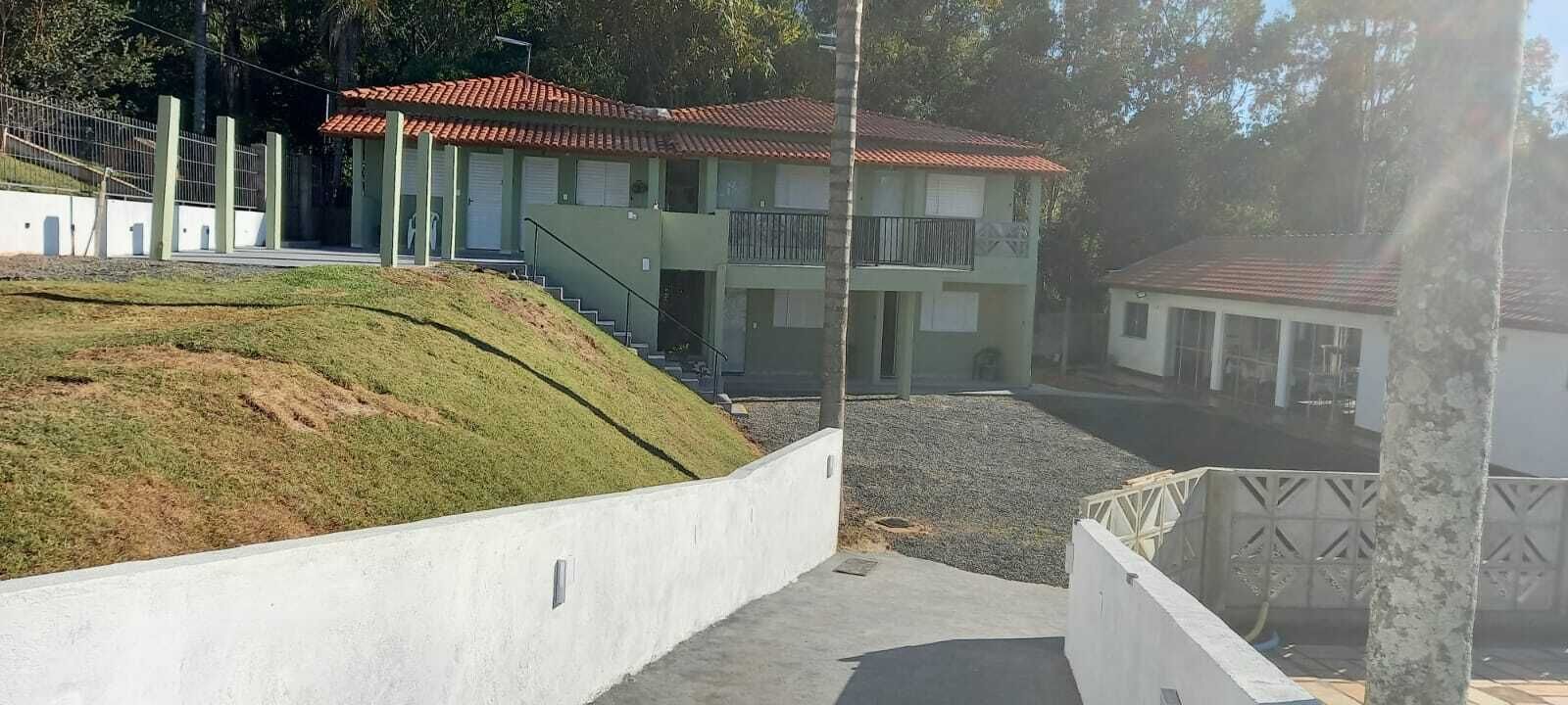A two-story building with a red-tiled roof, a staircase leading to the upper floor, and a small balcony.