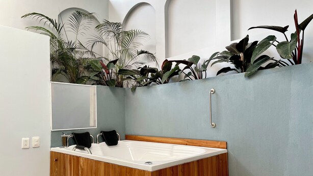 A modern bathroom with a wooden vanity, a white bathtub, and a small wooden stool. - Lalinde by Wynwood House (Medellín)