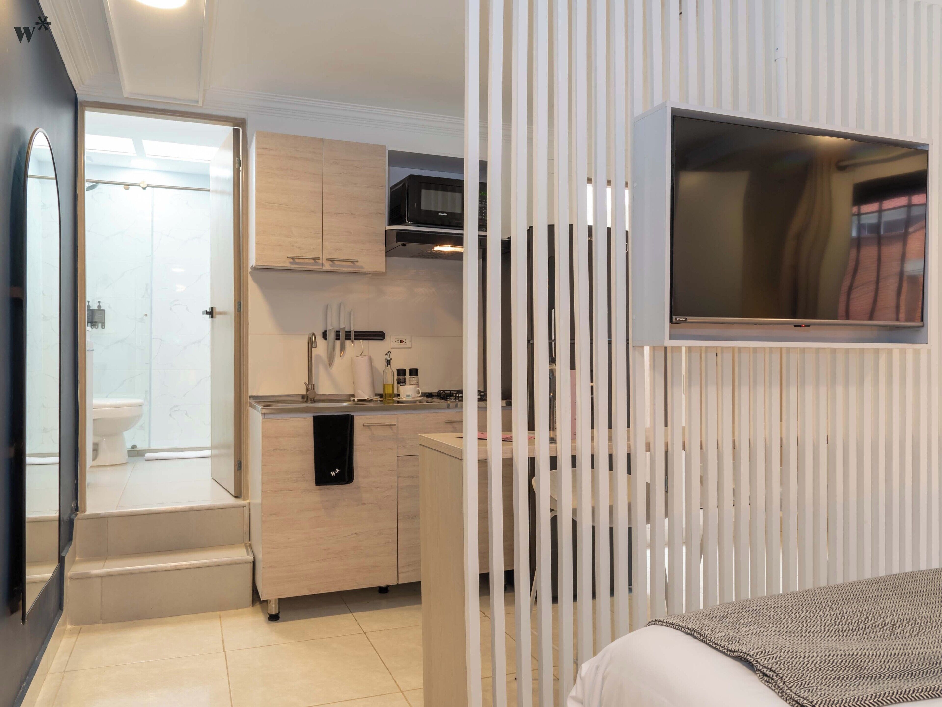 Ein modernes Hotelzimmer mit Küchenzeile, Dusche und Bett.