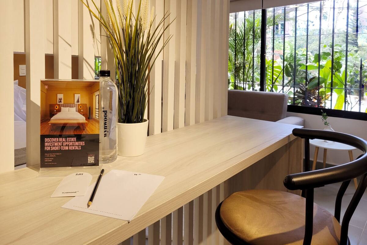 Un espacio de oficina moderno con un escritorio de madera, una silla, una planta en maceta y un folleto promocional.